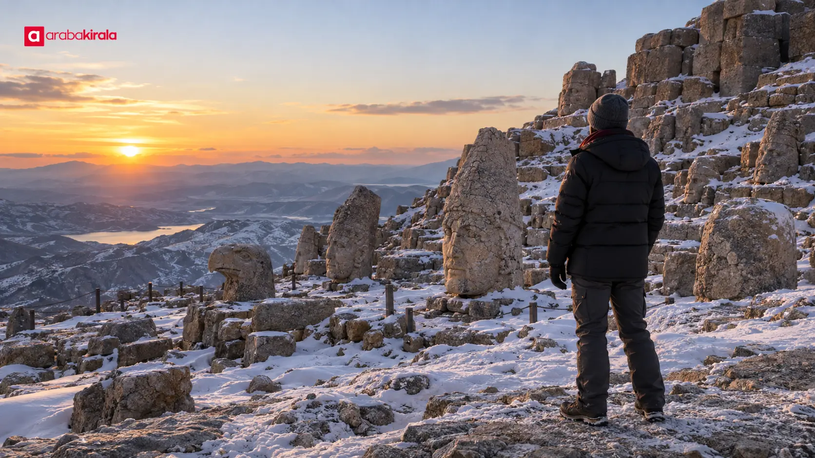 Soğuğa uygun giyinmiş bir ziyaretçi gün batımında Nemrut Dağı manzarasını izliyor Soğuğa uygun giyinmiş bir ziyaretçi gün batımında Nemrut Dağı manzarasını izliyor